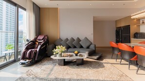 Una sala moderna con sillón de masaje, sofá gris y sillones naranjas.