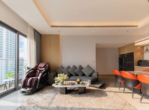 A modern living room with a massage chair, grey sofa, and orange chairs. - Adamas Boutique Hotel Nha Trang (Nha Trang)