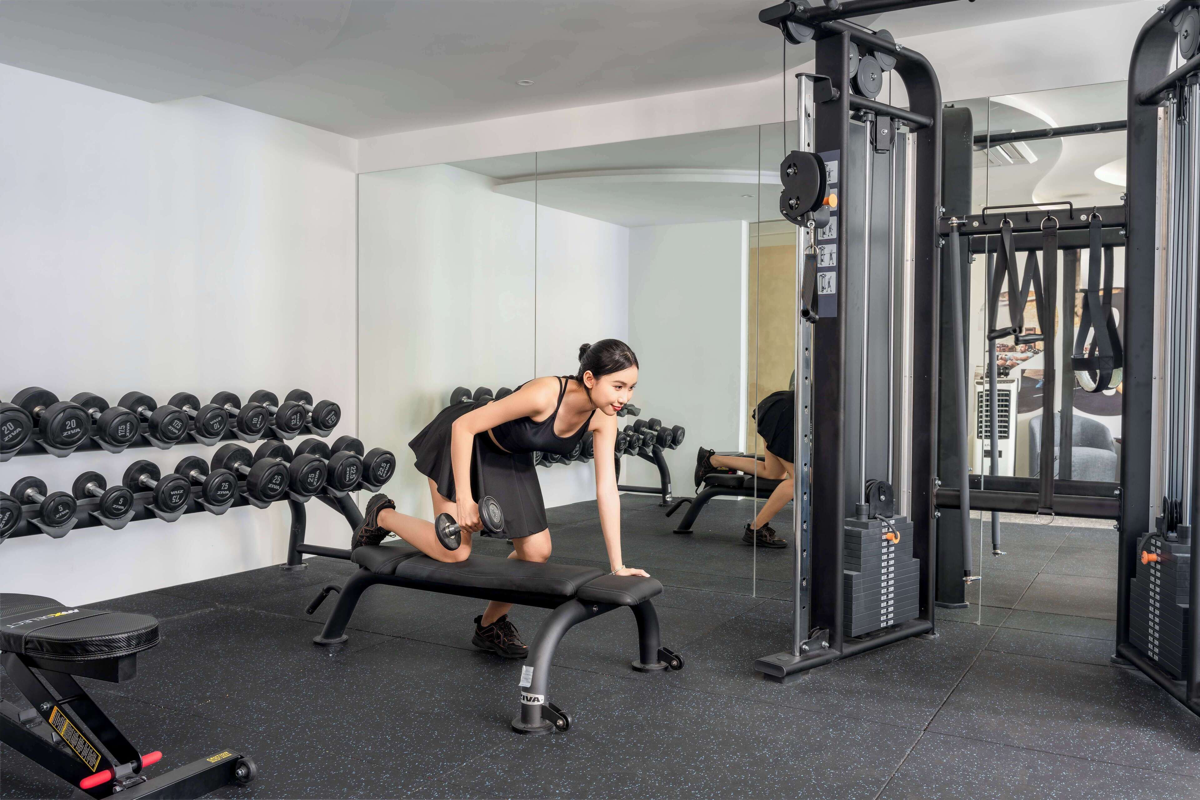 A gym with a bench, dumbbells, and weight machines.