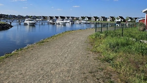 A marina with boats docked, a gravel path, and houses in the background. - Beaver Modern Retreat (Wandlitz)