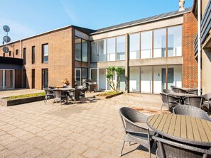 A modern building with a patio area featuring outdoor seating and a barbecue grill.