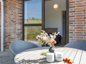 A round table with two white mugs, a vase with dried flowers, and a wicker chair. - 3 Person Holiday Park Home in Ulfborg (Ulfborg)