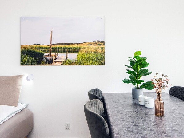 A dining area with a table, chairs, a potted plant, a vase, and a framed picture on the wall. - 3 Person Holiday Park Home in Ulfborg (Ulfborg)