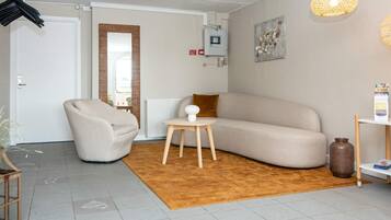 A modern living room with a beige sofa, a round wooden side table, and a brown rug.
