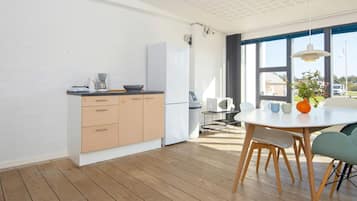 A modern kitchen with wooden cabinets, a white refrigerator, and a dining area with a round table and chairs.