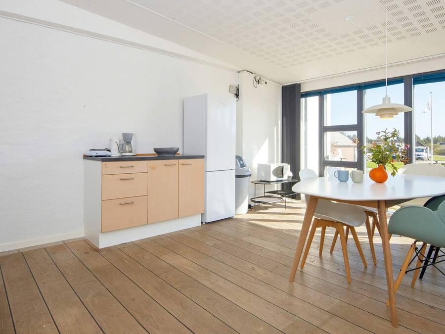 A modern kitchen with wooden cabinets, a white refrigerator, and a dining area with a round table and chairs.