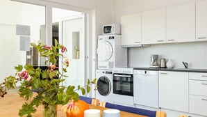 Une cuisine moderne avec des meubles blancs, un lave-linge, un four et un four à micro-ondes.
