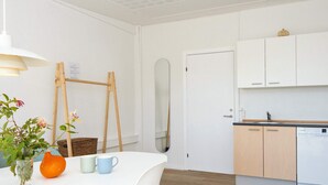 Une cuisine moderne avec des meubles blancs, un plancher en bois et un coin repas comprenant une table et des chaises blanches.