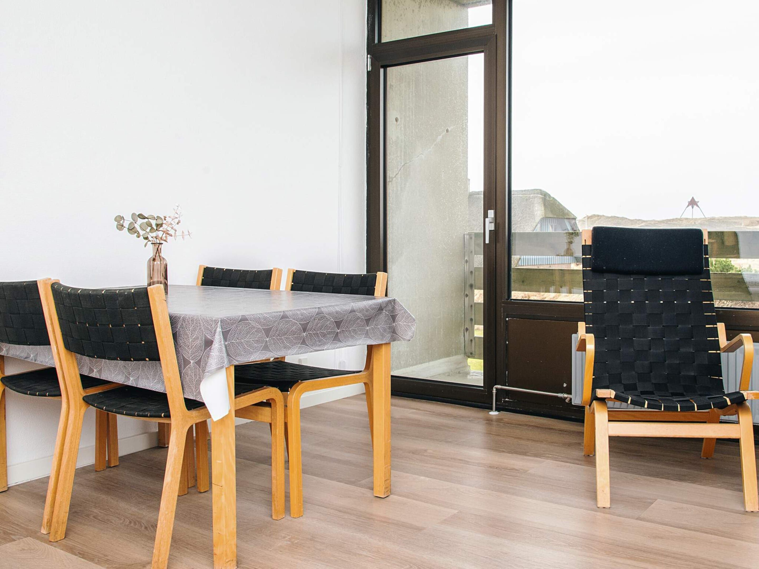 A dining area with a table, chairs, and a view through a glass door.