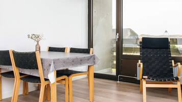 A dining area with a table, chairs, and a view through a glass door.
