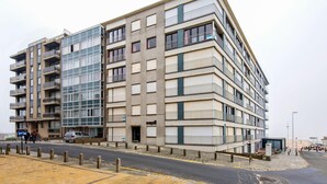Un immeuble à plusieurs étages doté de balcons, d’une entrée au niveau du sol et d’un espace de stationnement.