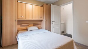 Une chambre à coucher comprenant un lit, une armoire en bois et une porte donnant sur une salle de bain.