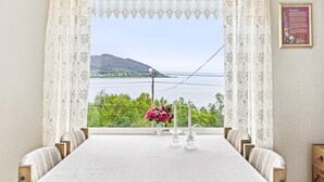 A dining area with a table set for two, a view of a lake and mountains, and a framed text on the wall. - 6 Person Holiday Home in Aram (Vanylven)