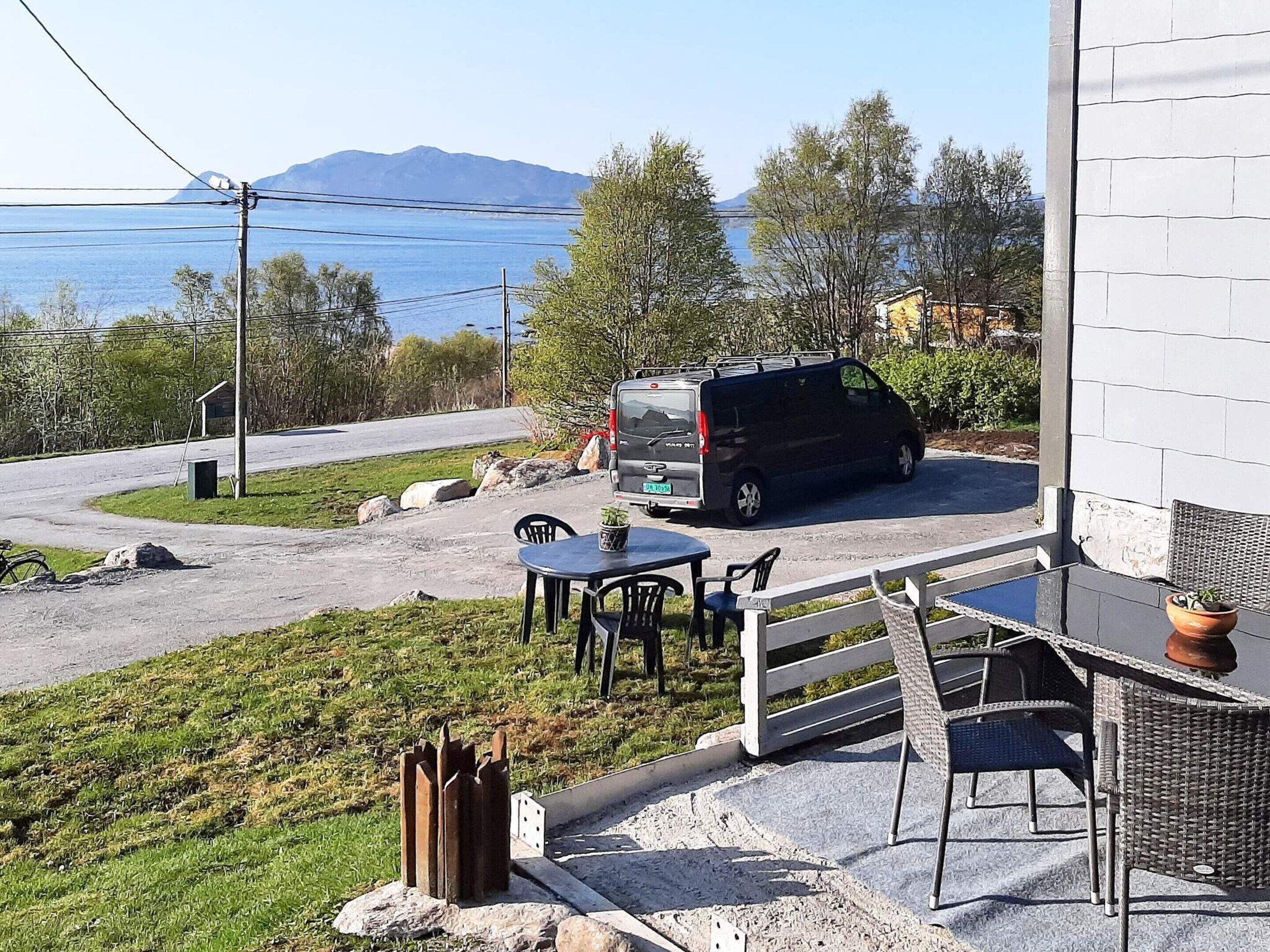 A van parked in a driveway with a table and chairs outside a building.