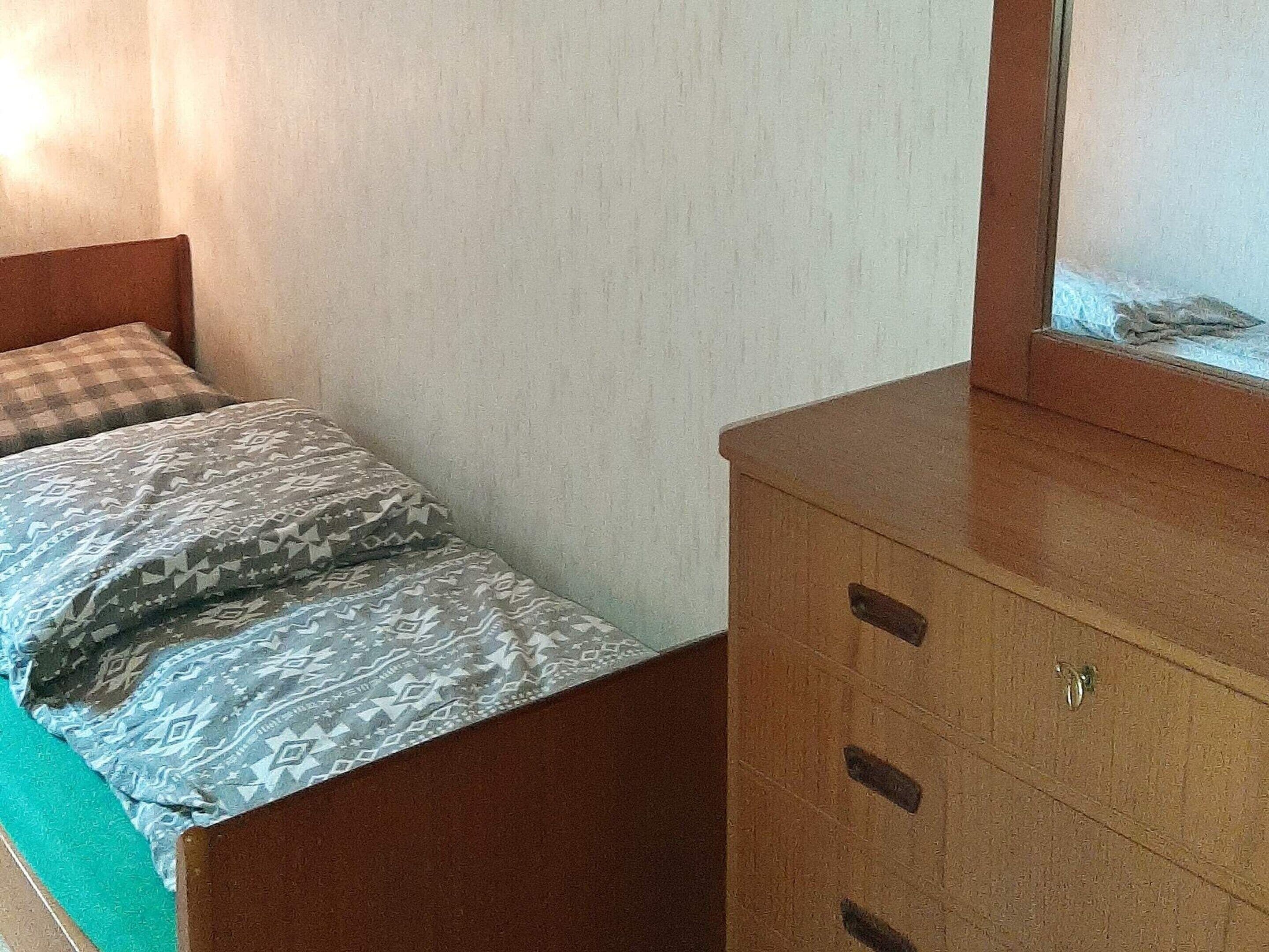 Een slaapkamer met een bed, een dressoir en een wandaquarium.