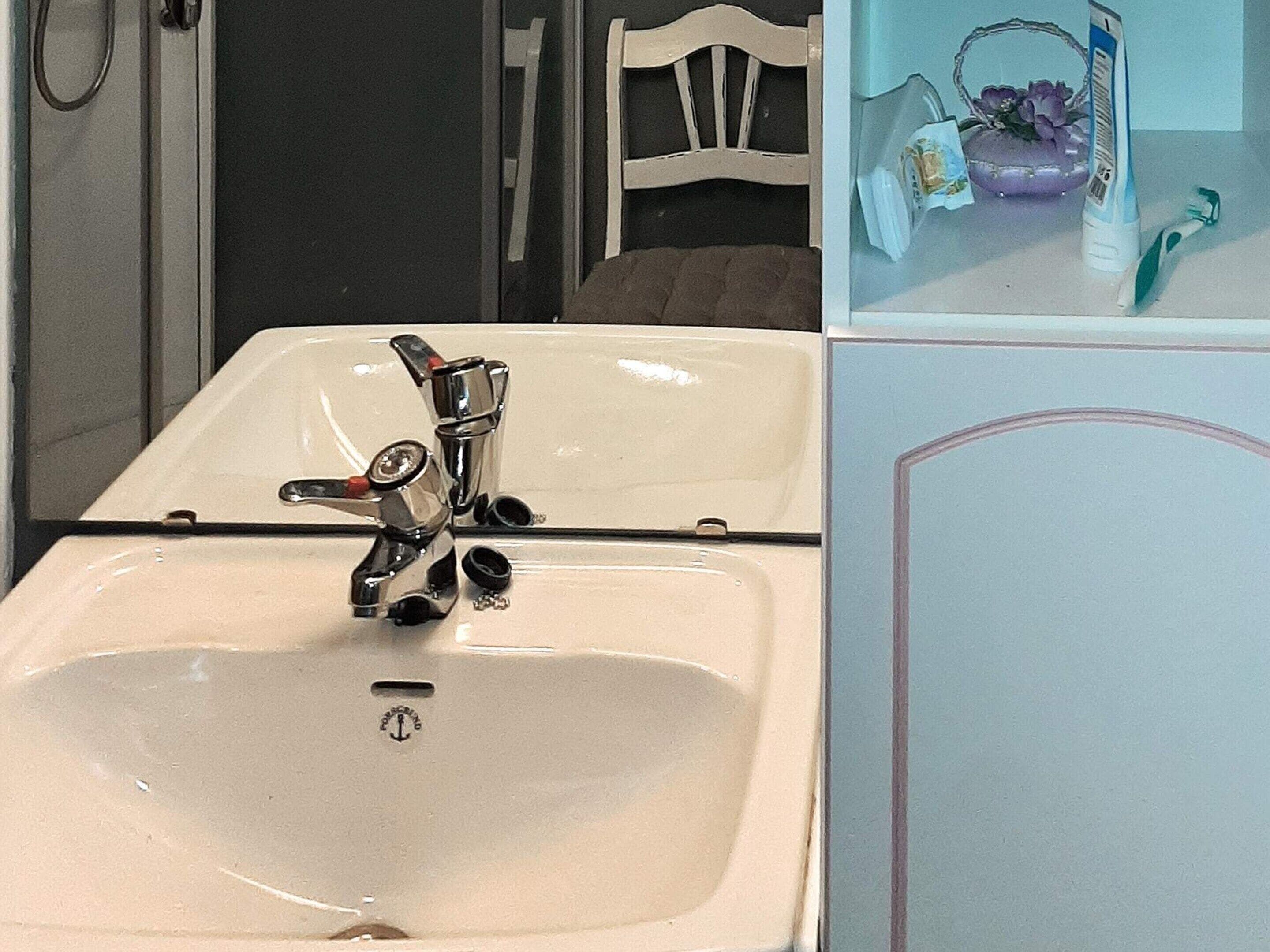 A bathroom with a white sink, chrome faucet, and a mirror.