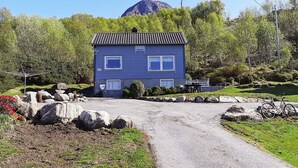 A blue house with a number '631' on the side, surrounded by greenery and a mountain in the background. - 6 Person Holiday Home in Aram (Vanylven)