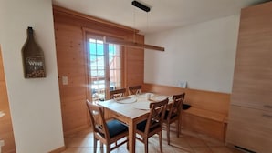 Un comedor con una mesa y sillas de madera, una ventana con vistas y un armario de madera.