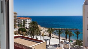 Vista costanera amb una platja, palmeres i un cel blau clar.