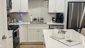 A modern kitchen with white cabinetry, a herringbone backsplash, stainless steel appliances, and a central island. - Back To College! 3 Bed Rooms 2.5 Bathroom- College Street near 280 (Auburn)