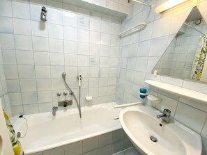 A bathroom with a bathtub, a sink, and a mirror. - Beachside Modern Retreat (Nieuwpoort)