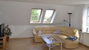 Un salón amplio con un sofá grande color beige, una mesa de centro de cristal y dos tragaluces.