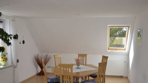 Un comedor con una mesa y sillas, una ventana con vistas y un radiador.
