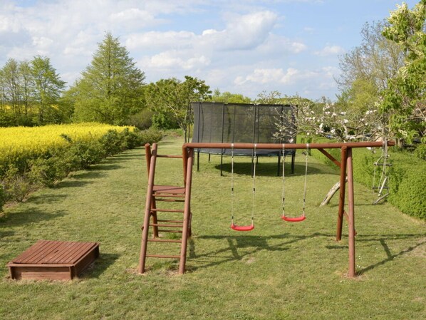 A wooden swing set in a grassy yard with a trampoline and a ladder. - Apartment in Feldberger Seenlandschaft (Feldberger Seenlandschaft)