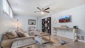 A living room with a sofa, coffee table, and a TV mounted on the wall. - Colorado Bay B (Colorado Springs)