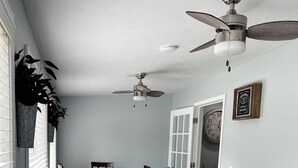 A dining area with a table and chairs, a ceiling fan, a clock, and a door leading to another room. - Cozy Cabin at Villager Resort on Lake Cumberland KY (Somerset)
