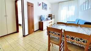 A compact living space with a dining area, kitchenette, and a bed. - Apartment in Caorle 500 m From Beach (Caorle)