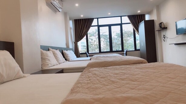 A hotel room with two beds, a large window with curtains, a flat-screen TV, and a wardrobe. - Nhat Bao Hotel Ha Giang - by Bay Luxury (Ha Giang 1)