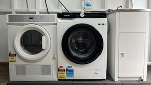 Una lavadora de carga frontal y una secadora una al lado de la otra, con una botella de detergente encima.