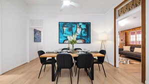 A dining area with a wooden table, black chairs, and a large abstract painting above. - Heritage 5BR Queenslander - Minutes walk to CBD & South Bank (Highgate Hill)