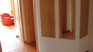 Un pasillo con armarios de madera y una silla roja.