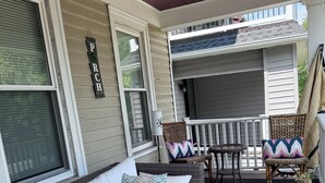 A covered porch with a wicker sofa, two chairs, a small table, and a potted plant. - Entire apt near Olmstead Delaware park, North Buffalo, Zoo, UB & 2 Hosp. (Buffalo)