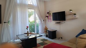 Ein Wohnzimmer mit einem schwarzen Couchtisch, einem an der Wand montierten Fernseher und einem Sofa.