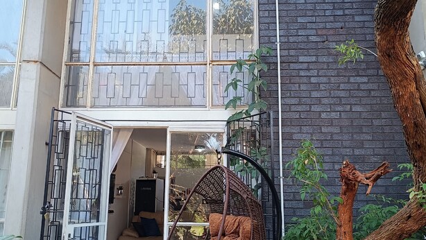 Ein modernes Haus mit einem großen Fenster, einem Hängesessel und einem Baum.