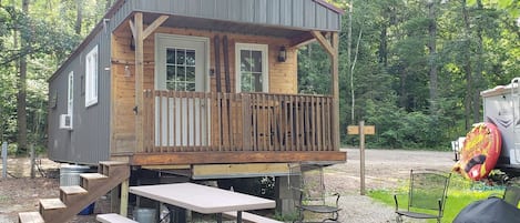 Una cabaña de madera con balcón, mesa de picnic y zona de barbacoa.