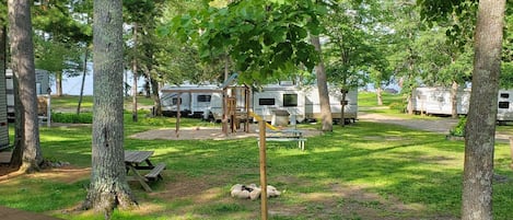 A campground with RVs, picnic tables, and a playground.