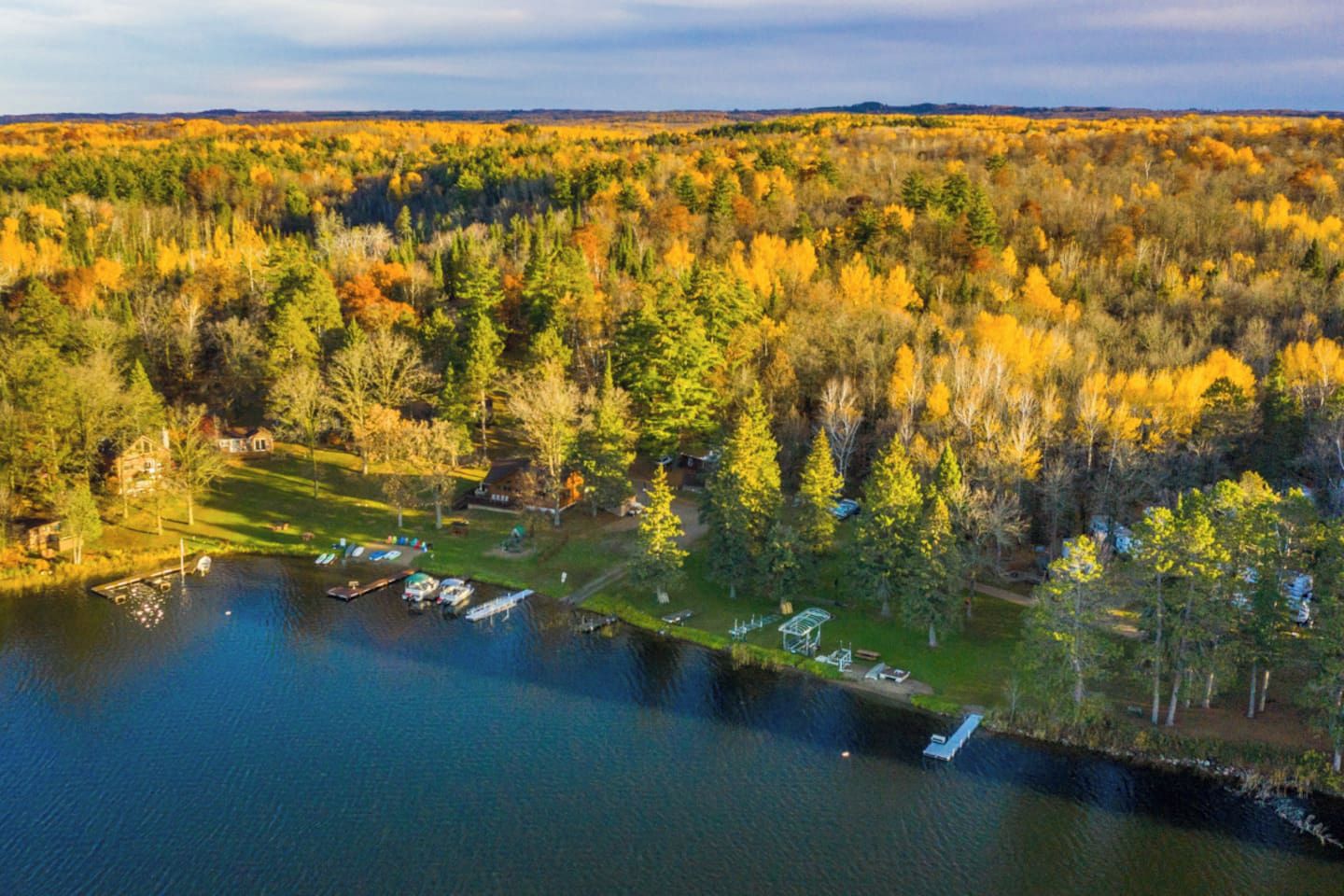 An aerial view of a lakeside property with a dock, a gazebo, and a forested area.