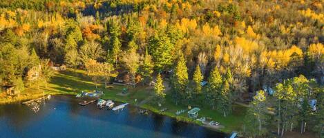 An aerial view of a lakeside property with a dock, a gazebo, and a forested area.