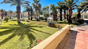A landscaped garden with palm trees and a paved walkway. - Apartment by Roquetas Beach (Roquetas de Mar)