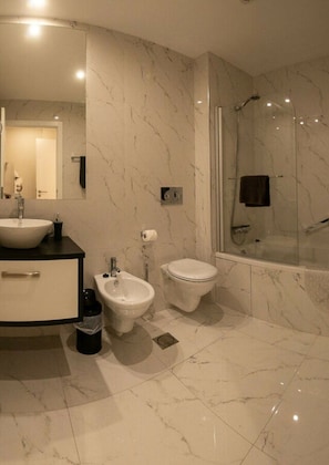 A modern bathroom with a marble floor, a sink, a bidet, a toilet, and a glass-enclosed shower area. - Madeira Mar "seaside" (Funchal)