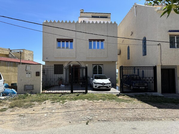 Una casa de dos pisos con un coche en la entrada.