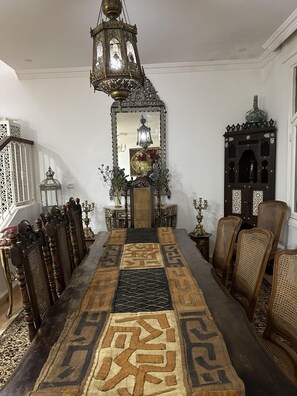 Un comedor tradicional con una larga mesa, sillas ornamentadas y un farol colgante.