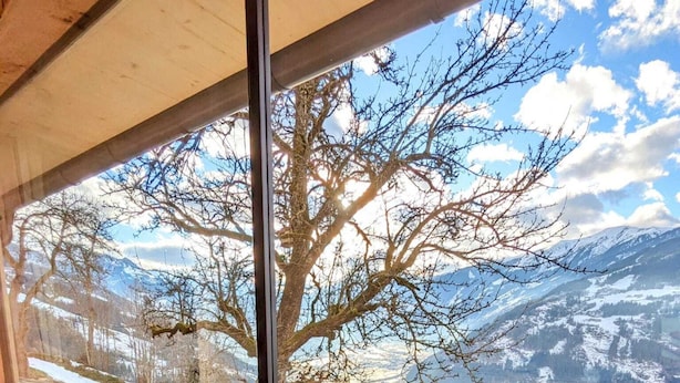 A wooden cabin with a large window overlooking a snowy mountain landscape. - Spacious Holiday Home in Distelberg With Sauna (Aschau Im Zillertal)