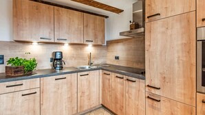A modern kitchen with wooden cabinets, a built-in stove, and a coffee maker. - Spacious Holiday Home in Distelberg With Sauna (Aschau Im Zillertal)