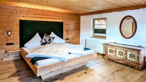 A wooden-paneled bedroom with a bed, a dresser, a window, and a mirror. - Spacious Holiday Home in Distelberg With Sauna (Aschau Im Zillertal)