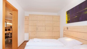 A hotel room with a wooden headboard, a large wooden wardrobe, and a bed with white bedding. - Apartment in Wald im Pinzgau Near the ski Lifts (Wald im Pinzgau)